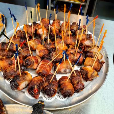 Bacon-wrapped dates served on a  round, metal platter.