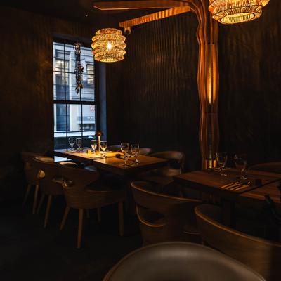 Dining area with set wooden tables, chairs and woven bamboo light fixtures.
