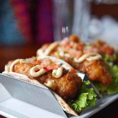 Fish tacos topped with pico de gallo and sauce drizzle.