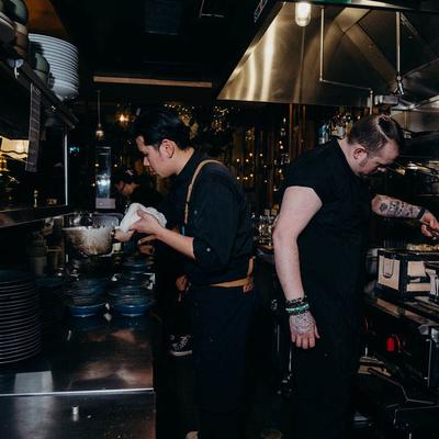 Chefs cooking surrounded by various equipment.
