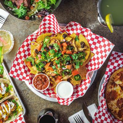 Various Mexican dishes and drinks on a table, including tacos and nachos.