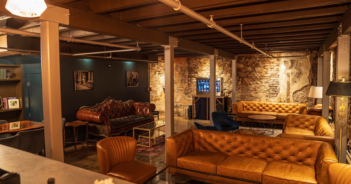 Lounge area with leather sofas, exposed stone walls, and warm lighting