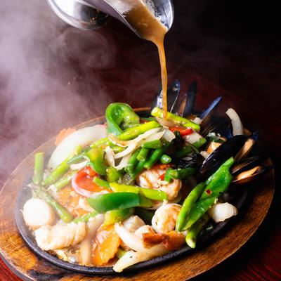 Mixed seafood and veggies served on a hot plate.