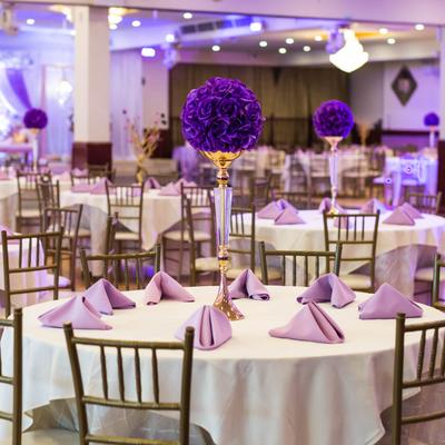 Banquet hall, skirted tables with violet napkins and violet floral decoration