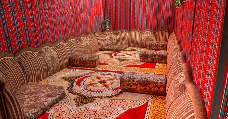 Interior, padded floor seating in a traditional Arabic style, scattered cushions