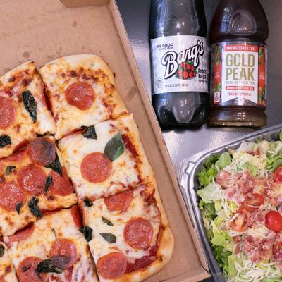 A family pack - a pizza, a chopped salad and beverages, top view.