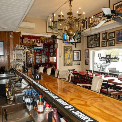 Interior with a wooden bar counter, set tables, wall art, and chandeliers.
