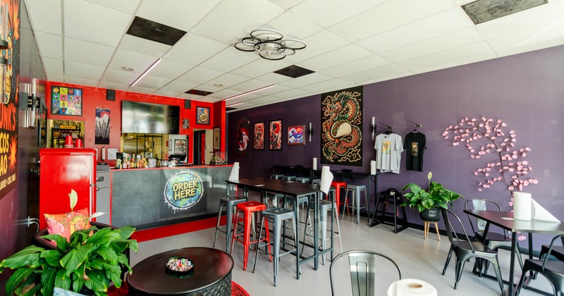 Interior with a service counter, dragon artwork, cafe seating, plants, and pink blossomed wall decor