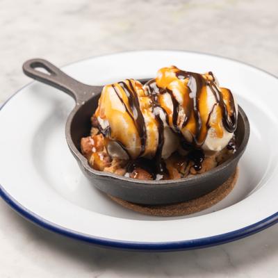 Chocolate chip cookie skillet dessert topped with ice cream.
