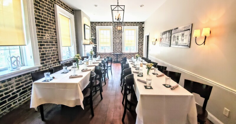 Dining room with brick walls, set tables with flowers, and wall art