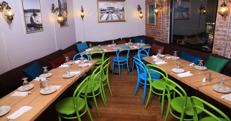 Interior with L-shaped tables, colorful chairs, and cushioned benches