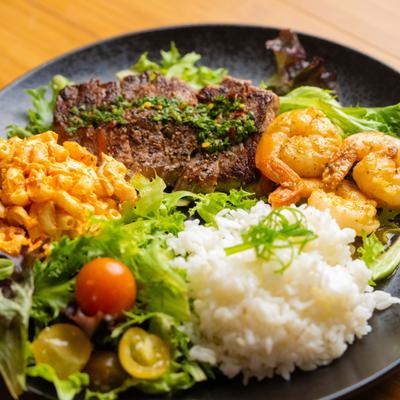 Grilled Steak and Garlic Shrip mix plate with various sides.