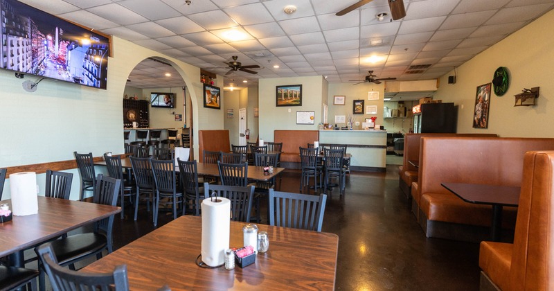 Restaurant dining area with wood tables, brown booths, and ceiling fans