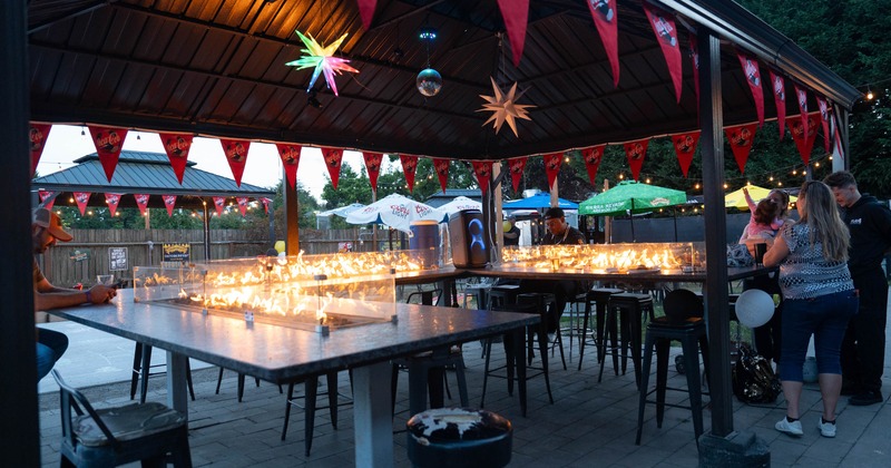Decorated patio with tables featuring flaming built in fire pits