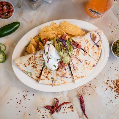 Pork quesadillas served with tortilla chips, guacamole, and sour cream.