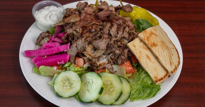 Roasted beef cut into thin slices and served with pita, vegetables, and a sauce