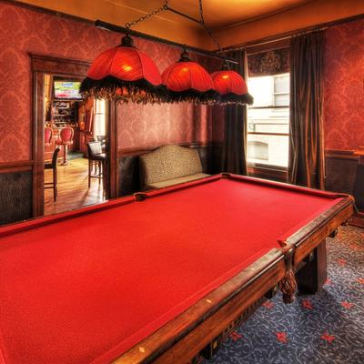 Red Pool table with comfy chair and windows