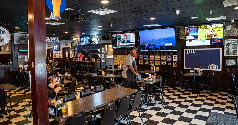 Interior, diner area, tables and chairs, tv's,  waiter and guest