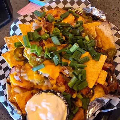 Nacho, loaded with melted cheese, meat and jalapeños, topped  with green onion.