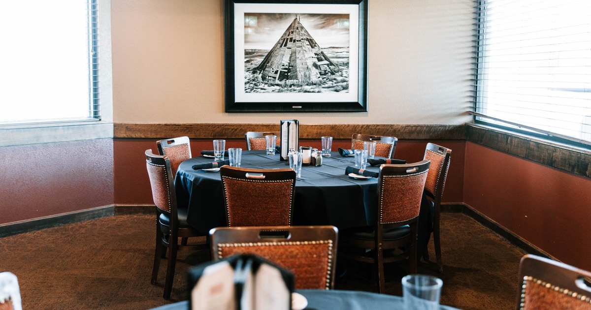 A round table with a black tablecloth and surrounded by chairs