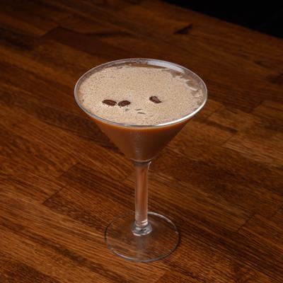 Espresso Martini with coffee bean garnish on a wooden table.