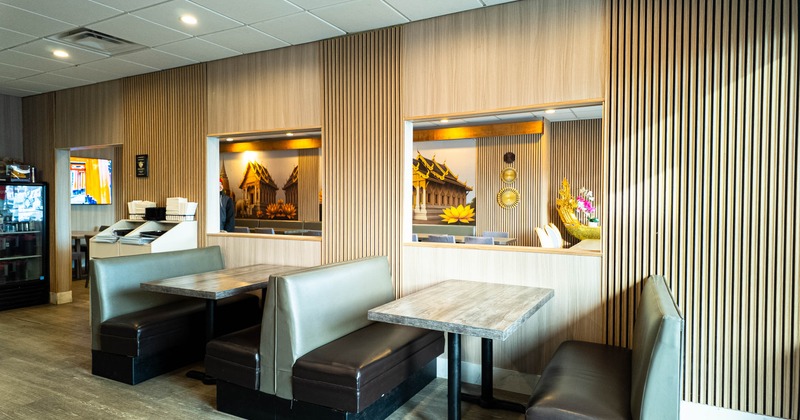 Interior of a restaurant with booth seating and a vibrant mural of Thai architecture