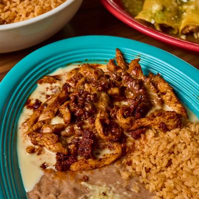 Grilled chicken strips and chorizo topped with cheese, served with rice and beans.