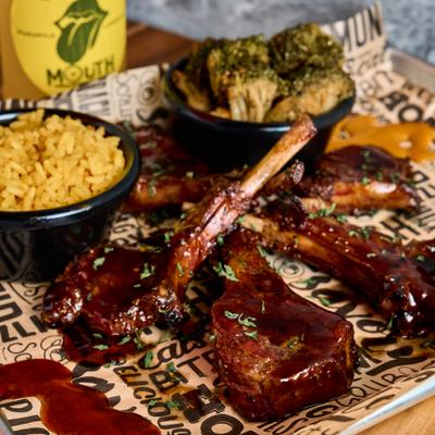 Lamb chops glazed with barbecue sauce, served with rice and cooked broccoli.