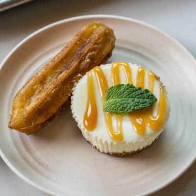 Churros and a mini cheesecake with caramel sauce and mint.