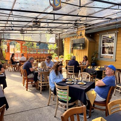 Patrons dining outdoors on a covered restaurant patio.
