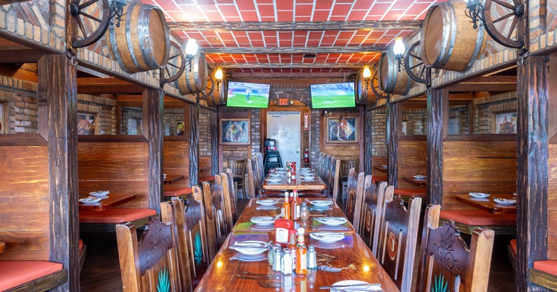 Interior of a rustic restaurant featuring a long dining table set for a meal, wooden chairs