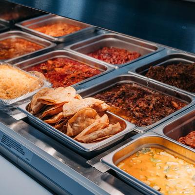 Food bar display compartments filled with assorted dishes.