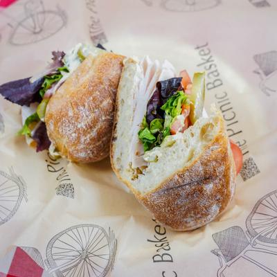 Turkey sandwich served on ciabatta bread with greens and other condiments.
