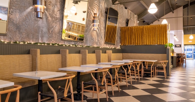 A restaurant interior with a checkered floor, booths and large mirrors