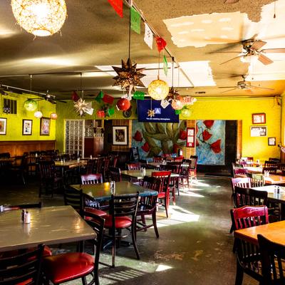 Vibrant dining room featuring tables, yellow walls, paper decorations, and wall art.