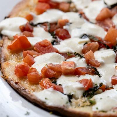 Bruschetta pizza, with diced tomatoes, olive oil, garlic, onions, basil, and mozzarella.