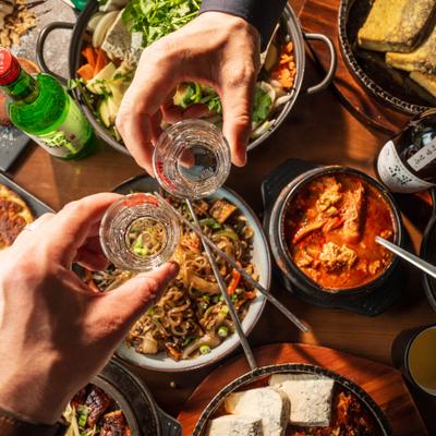Two hands clinging glasses over the table with various dishes, overhead view.