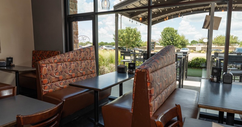 Interior, dining area, seating booths by the large shop window overlooking the patio