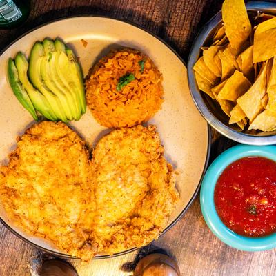 Breaded chicken breast with Mexican rice, avocado, salsa, and tortilla chips.
