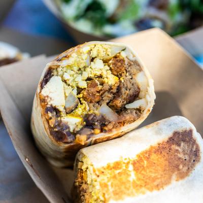 Big Brunch Burrito sliced in half and served in a cardboard box.