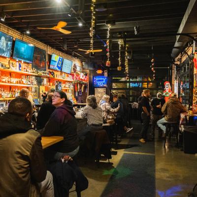 Interior of bar area with multiple televisions and people seating at the bar.