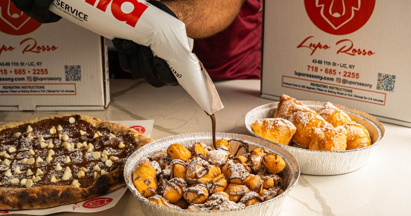 Chocolate sauce being drizzled over mini donuts with desserts in the background