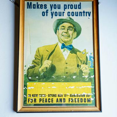 Framed vintage poster featuring a person in a suit and text Makes You Proud of Your Country.