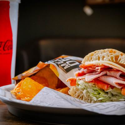Turkey club sub served with chips and coke.