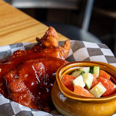 Jumbo Tenders topped with a red sauce, served with chopped cucumber and tomato.