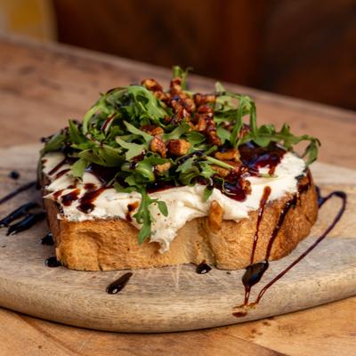 Goat cheese toast topped with arugula, berry jam, toasted pecans, and balsamic drizzle.