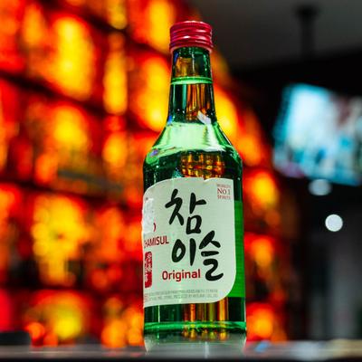 Bottle of soju served on a counter with bar in the background.