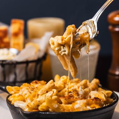 Mac and cheese on a fork, cheese pool shot.