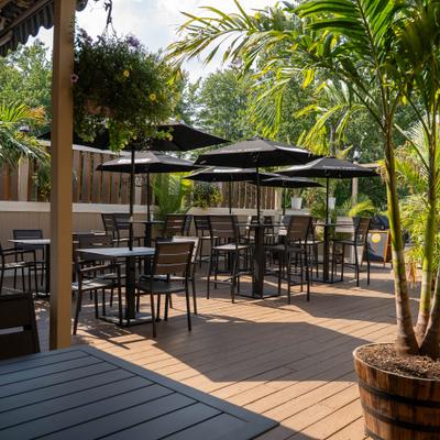 Outdoor dining deck with wooden furniture and multiple black umbrellas.