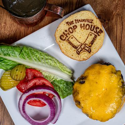 Cheeseburger served with romaine lettuce, tomato, red onion, and pickle, top view.